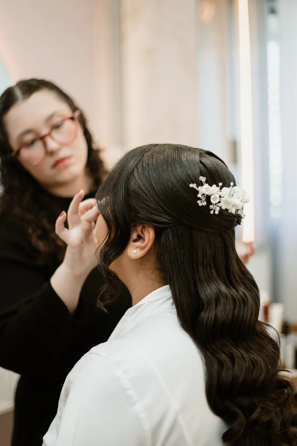 Janaína finalizando um penteado com ondas e acessório de noiva