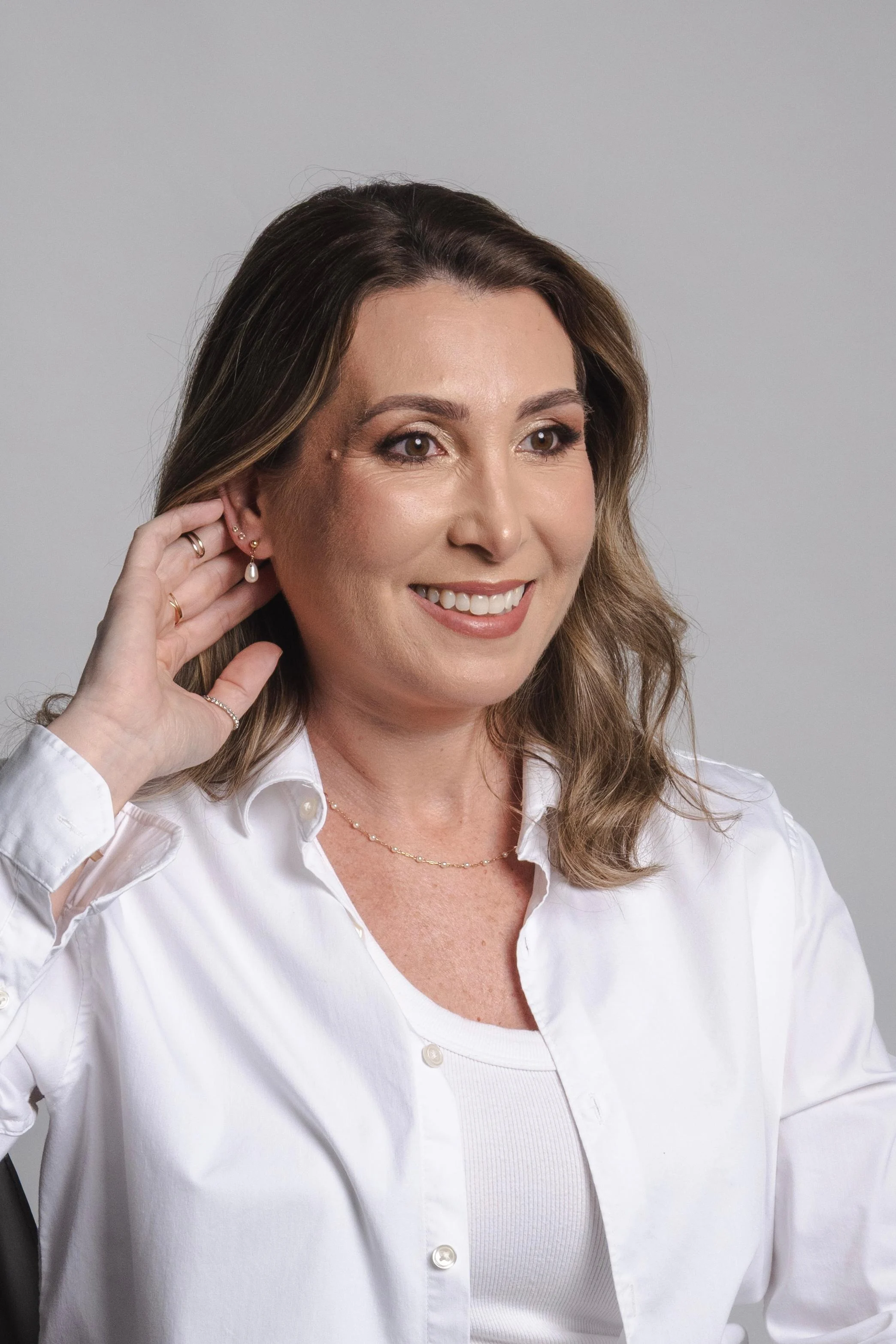 Maquiagem com olhos definidos e cabelo solto com ondas em mulher de camisa branca