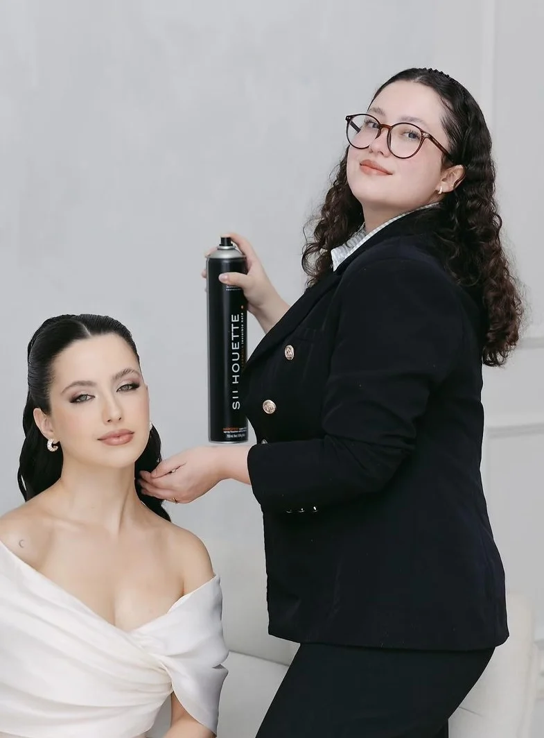 Janaína fixa com spray o penteado de uma modelo durante a aula